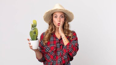 Oldukça zayıf bir kadın elinde kaktüs tutarken şok olmuş ve korkmuş hissediyor. çiftçi kavramı