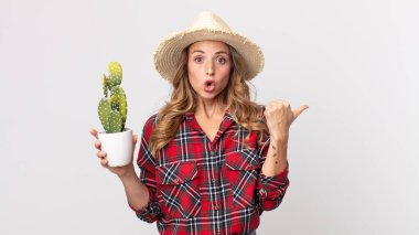 Elinde bir kaktüs tutmaktan şaşkın şaşkın bakan oldukça zayıf bir kadın. çiftçi kavramı