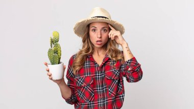 Oldukça zayıf bir kadın şaşırmış görünüyor. Elinde kaktüs tutan yeni bir düşünce, fikir ya da konsept fark ediyor. çiftçi kavramı