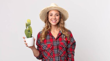Oldukça zayıf bir kadın mutlu görünüyor ve elinde bir kaktüs tutarken oldukça şaşırmış görünüyor. çiftçi kavramı