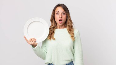 Oldukça zayıf bir kadın. Şok olmuş ya da şaşırmış görünüyor. Elinde boş bir tabakla boş bir tabak tutuyor.