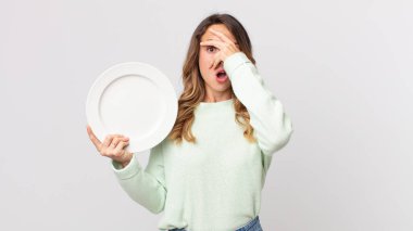 Oldukça zayıf bir kadın şok olmuş, korkmuş ya da korkmuş görünüyordu. Yüzü elle kaplıydı ve boş bir tabak tutuyordu.