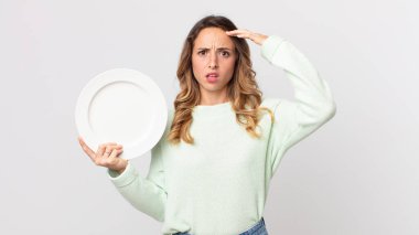 Kafası karışmış, kafası karışmış, kafası karışmış bir kadın. Elinde boş bir tabak tutarak deli olduğunu gösteriyor.