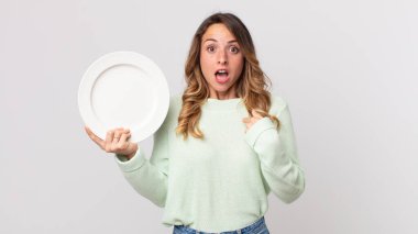 Oldukça zayıf bir kadın ağzı açık, ağzı açık, boş bir tabak tutan ve boş bir tabak tutan oldukça şaşkın ve şaşırmış görünüyordu.