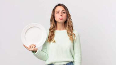 Oldukça zayıf bir kadın üzgün ve mızmızlanıyor. Mutsuz görünüyor ve ağlıyor. Elinde boş bir tabakla boş bir tabak tutuyor.