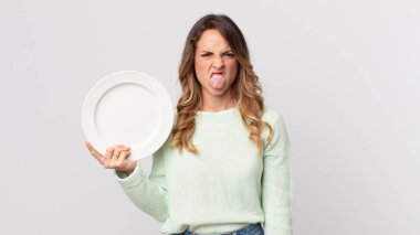 Oldukça zayıf bir kadın midesi bulanmış ve rahatsız olmuş hissediyor. Dilini çıkarıp boş bir tabak tutuyor ve elinde boş bir tabak tutuyor.