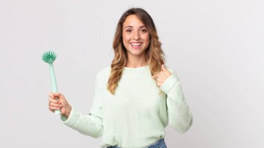 Oldukça zayıf bir kadın kendini mutlu hissediyor ve heyecanlı ve bulaşık fırçasıyla kendini işaret ediyor.