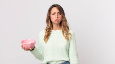 Oldukça zayıf bir kadın üzgün ve mızmızlanıyor. Mutsuz bir bakışla, ağlıyor ve elinde boş bir demlik tutuyor.