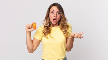 İnanılmaz bir sürprizle şaşkın, şaşkın ve afallamış ve elinde pillerle oldukça zayıf bir kadın.