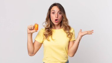 Oldukça zayıf bir kadın şaşırmış ve şok olmuş görünüyor, çenesi düşmüş, elinde bir nesne ve elinde pillerle.