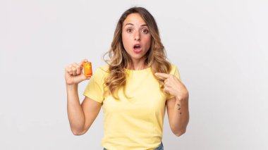 Ağzı açık, kendini gösteren ve elinde pil tutan oldukça zayıf ve şaşkın görünen bir kadın.