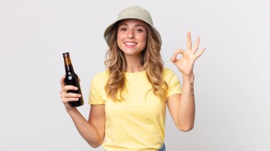 Oldukça zayıf bir kadın kendini mutlu hissediyordu. Onayını gösteriyordu. İyi bir jestle ve elinde birayla. yaz konsepti