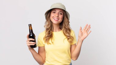 Oldukça zayıf bir kadın mutlu bir şekilde gülümsüyor, el sallıyor, seni selamlıyor ve bira tutuyor. yaz konsepti