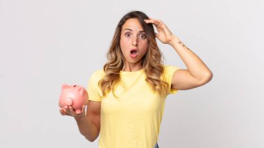 Mutlu, şaşkın, şaşırmış ve elinde bir kumbara tutan oldukça zayıf bir kadın.