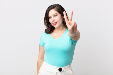 Güzel bir kadın gülümsüyor ve arkadaş canlısı görünüyor. İki ya da iki numarayı gösteriyor. Elleri önde, geri sayıyor.