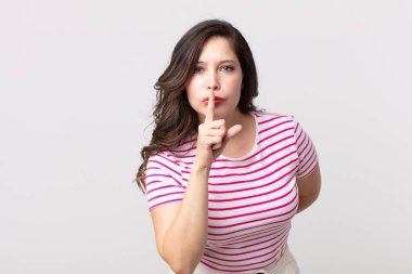 Güzel bir kadın sessizlik ve sessizlik istiyor, parmaklarıyla ağzının önünde işaret ediyor, 