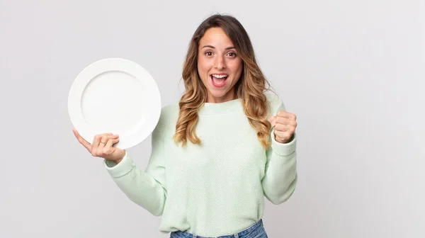 とても薄い女性はショックを受け笑って成功を祝い空の皿を持って空の皿を持っています — ストック写真