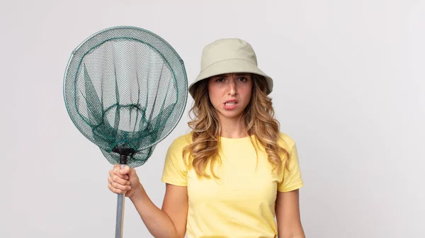 pretty thin woman feeling puzzled and confused wearing hat and holding a fish net