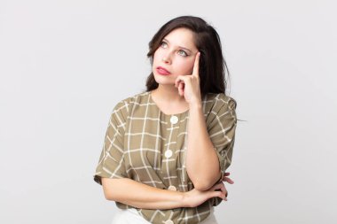 Yoğunlaşmış bakışları olan güzel bir kadın şüpheli bir ifadeyle yukarı ve yana bakıyor.