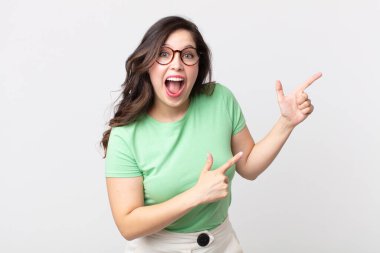 Güzel bir kadın mutlu ve şaşırmış hissediyor, şok olmuş bir ifadeyle gülümsüyor ve bir tarafı işaret ediyor.