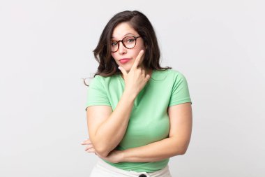 Güzel bir kadın ciddi, düşünceli ve güvensiz görünüyor, bir kolu çapraz ve elleri çenesinde, seçenekleri değerlendiriyor.