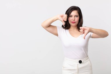 Güzel bir kadın üzgün, hayal kırıklığına uğramış ya da kızgın görünüyor, anlaşmazlık içinde başparmaklarını gösteriyor, hayal kırıklığına uğramış hissediyor.