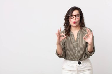 Güzel bir kadın şok olmuş, şaşırmış ve şaşırmış hissediyor. Onaylıyor. İki eliyle de onay işareti yapıyor.