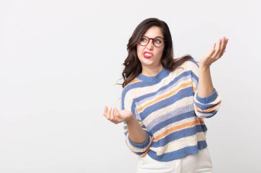 pretty woman shrugging with a dumb, crazy, confused, puzzled expression, feeling annoyed and clueless