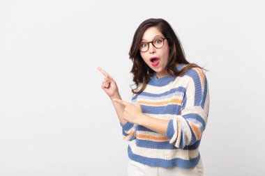 Güzel bir kadın mutlu ve şaşırmış hissediyor, şok olmuş bir ifadeyle gülümsüyor ve bir tarafı işaret ediyor.