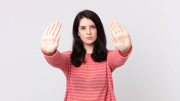 pretty woman looking serious, unhappy, angry and displeased forbidding entry or saying stop with both open palms