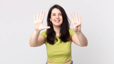 Güzel bir kadın gülümsüyor ve arkadaş canlısı görünüyor. 9 ya da 9 numarayı gösteriyor. Elleri önde ve geri sayıyor.