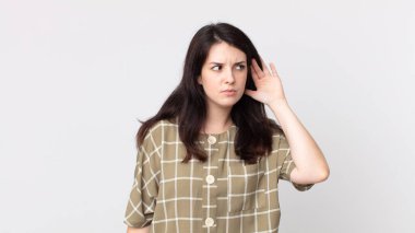 Güzel kadın ciddi ve meraklı görünüyor, dinliyor, gizli bir konuşma veya dedikodu duymaya çalışıyor, kulak misafiri oluyor.