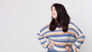 Güzel bir kadın mutlu, neşeli ve kendinden emin görünüyor. Gururla gülümsüyor ve iki elini de kalçasında istiyor.