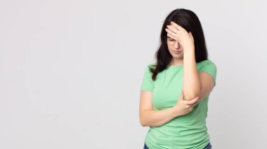 Güzel bir kadın stresli, utanmış ya da üzgün görünüyor, baş ağrısı var, yüzünü elleriyle kapatıyor.