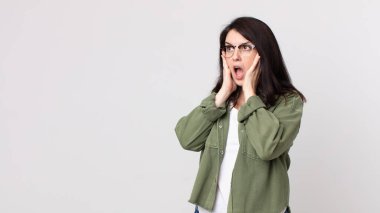 Güzel bir kadın mutlu, heyecanlı ve şaşırmış hissediyor, iki eli yüzü üzerinde yana bakıyor.