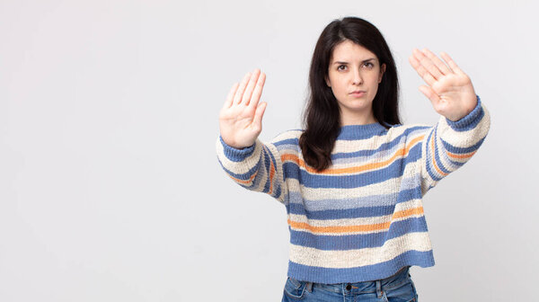 pretty woman looking serious, unhappy, angry and displeased forbidding entry or saying stop with both open palms