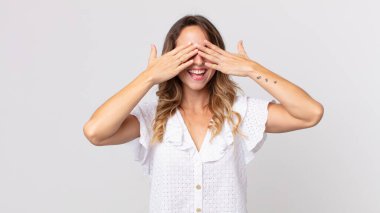 Gülümseyen ve mutlu hisseden zayıf bir kadın. İki eliyle gözlerini kapatıyor ve inanılmaz bir sürpriz bekliyor.