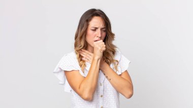 Boğazı ağrıyan, grip semptomları gösteren, ağzı kapalı öksüren zayıf bir kadın.