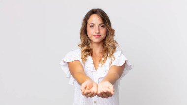 Oldukça zayıf bir kadın mutlu bir şekilde gülümsüyor, arkadaş canlısı, kendine güvenen, olumlu bakışlı, bir nesne ya da konsept sunan ve gösteren