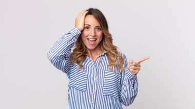 Oldukça zayıf bir kadın gülüyor, mutlu, pozitif ve şaşırmış görünüyor, yanal fotokopi alanını işaret eden harika bir fikrin farkına varıyor.