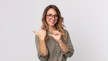 Oldukça zayıf bir kadın neşeli bir şekilde gülümsüyor ve yan taraftaki fotokopi alanını işaret ediyor, mutlu ve tatmin olmuş hissediyor.