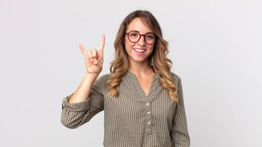 Oldukça zayıf bir kadın kendini mutlu, eğlenceli, kendinden emin, pozitif ve asi hissediyor, elle kaya ya da heavy metal işareti yapıyor.