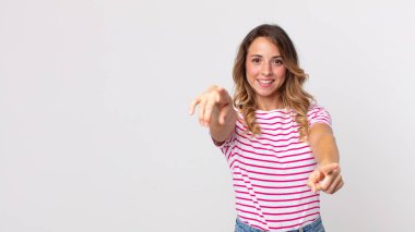 Oldukça zayıf bir kadın mutlu ve kendinden emin, kamerayı iki eliyle gösteriyor ve gülüyor, seni seçiyor.