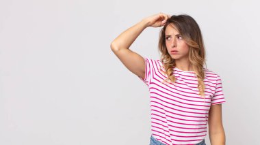 Kafası karışmış, kafası karışmış, başını kaşıyan ve yan tarafa bakan ince bir kadın.