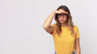 Oldukça zayıf bir kadın şaşkınlık ve şaşkınlık içinde bakıyor, el üstünde, uzaklara bakıyor, izliyor ya da arıyor.