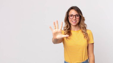 Oldukça zayıf bir kadın gülümsüyor ve arkadaş canlısı görünüyor, 5 ya da 5 numarayı gösteriyor, elleri önde, geri sayıyor.