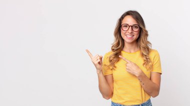 Oldukça zayıf bir kadın mutlu bir şekilde gülümsüyor ve her iki elini de fotokopi uzayında nesne göstererek yukarı ve yana doğru gösteriyor.