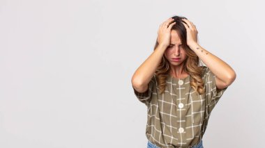 Oldukça zayıf bir kadın kendini stresli ve hayal kırıklığına uğramış hissediyor, elele tutuşuyor, yorgun, mutsuz ve migren ağrısı çekiyor.