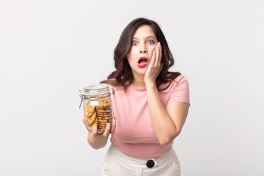 Güzel kadın şok olmuş ve korkmuş hissediyor ve elinde cam bir kurabiye şişesi tutuyor.