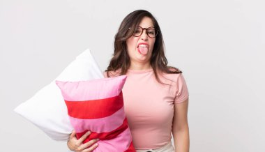 Güzel bir kadın midesi bulanmış ve rahatsız olmuş hissediyor ve pijama giyerek ve yastık tutarak dilini dışarı çıkarıyor.